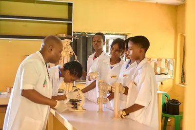 Teacher guiding students through microscope work in the biology laboratory